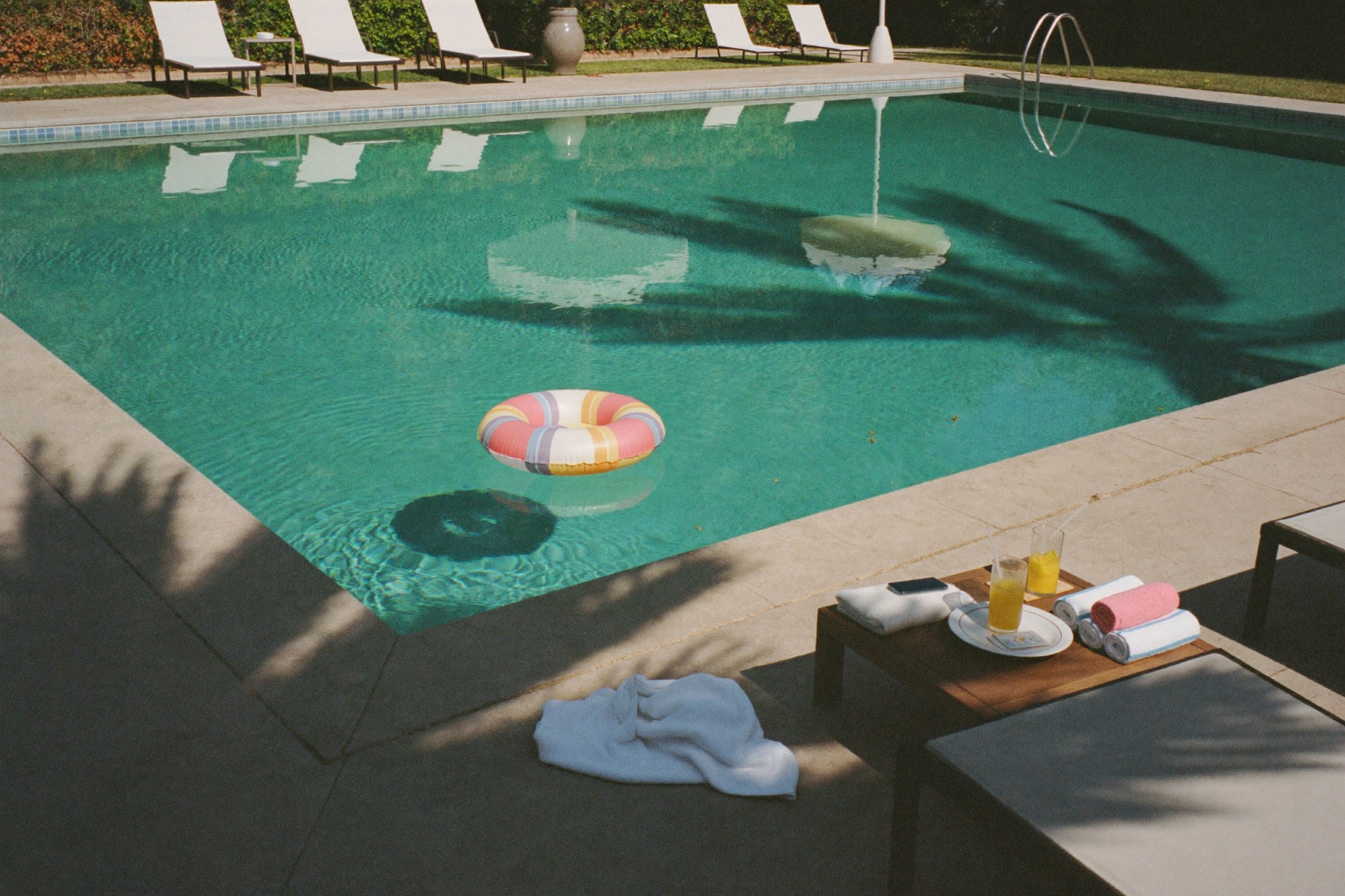 A serene pool on a Saturday morning with a float drifting and towels ready